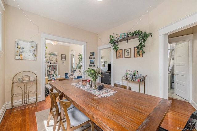 dining space with baseboards, ceiling fan, and wood finished floors