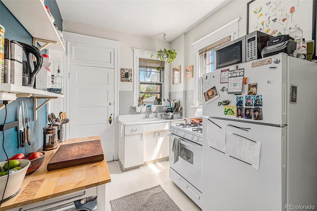 kitchen featuring white appliances, light countertops, light tile patterned floors, white cabinets, and backsplash