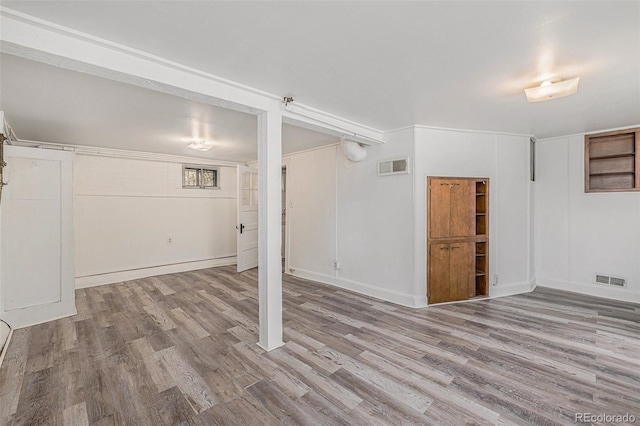 basement featuring visible vents, baseboards, and wood finished floors