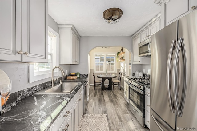 kitchen featuring light hardwood / wood-style flooring, stainless steel appliances, a textured ceiling, white cabinets, and sink