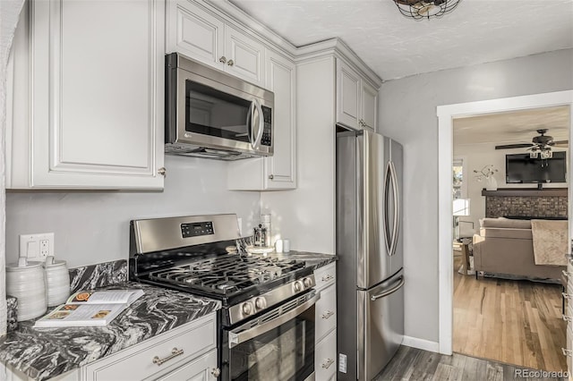 kitchen featuring ceiling fan, white cabinets, appliances with stainless steel finishes, and hardwood / wood-style floors