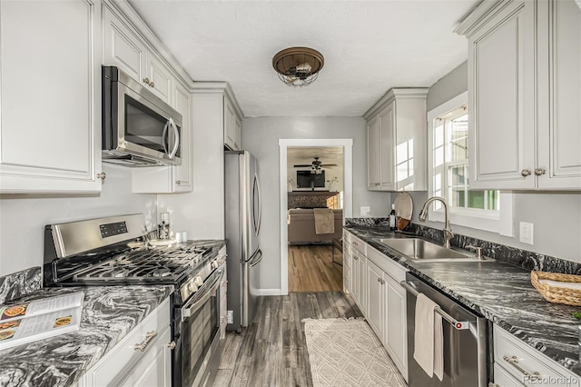 kitchen with white cabinetry, ceiling fan, appliances with stainless steel finishes, dark wood-type flooring, and sink