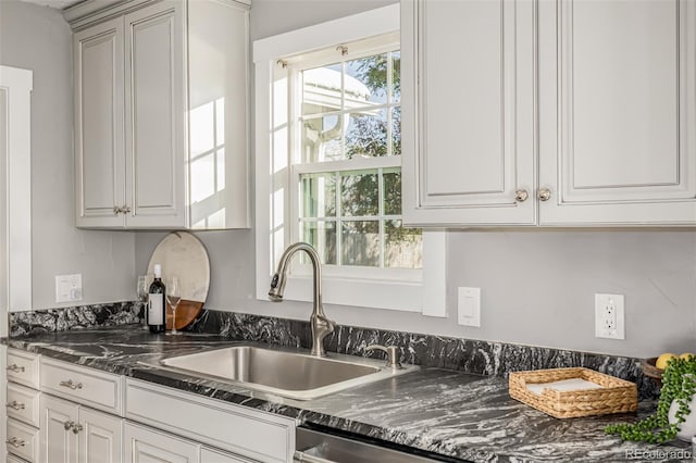 kitchen featuring sink, white cabinets, and dark stone countertops