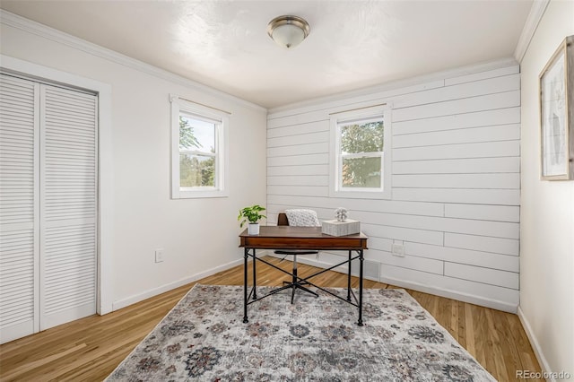 office area with wooden walls, ornamental molding, and light wood-type flooring