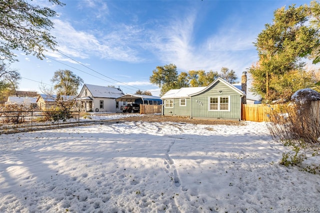 snow covered back of property with a carport