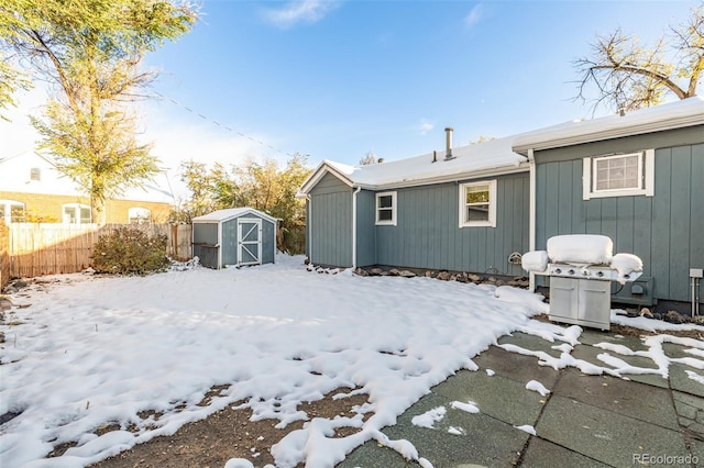 snow covered back of property with a storage shed