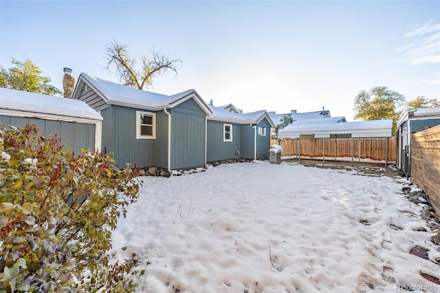 snow covered rear of property with an outbuilding