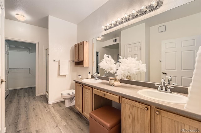 4221 S Blackhawk Cir Unit 7G, Aurora, CO 80014 - bathroom with wood finished floors, double vanity, a stall shower, and a spacious closet