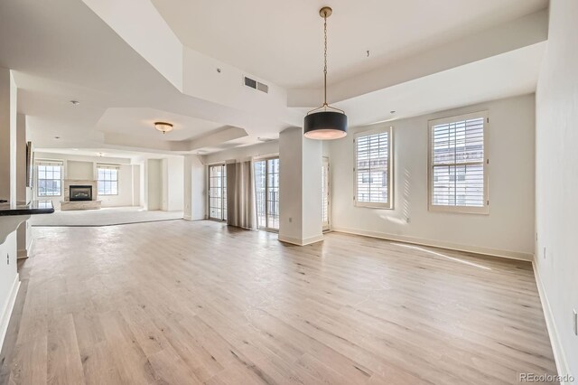475 W 12th Ave Unit 9A, Denver, CO 80204 - unfurnished living room with baseboards, light wood-style floors, a tray ceiling, and a fireplace