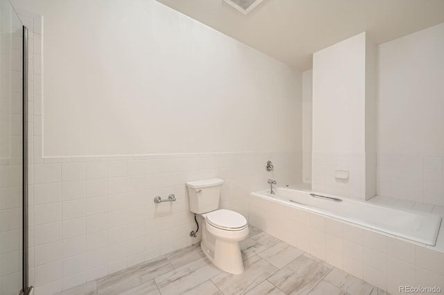 475 W 12th Ave Unit 9A, Denver, CO 80204 - bathroom featuring toilet, a bath, tile walls, and wainscoting