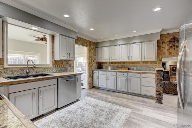 kitchen featuring ceiling fan, sink, stainless steel appliances, light hardwood / wood-style floors, and decorative backsplash