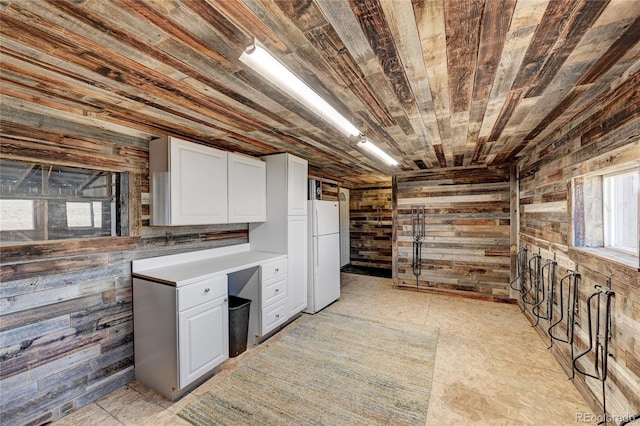 basement featuring white fridge, wood walls, and wooden ceiling