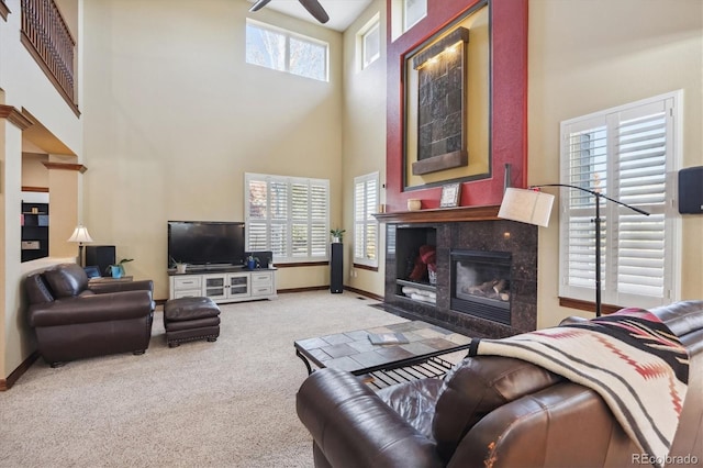 living area featuring light carpet, a fireplace, a towering ceiling, and baseboards