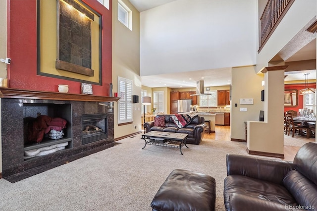 living room with baseboards, a high end fireplace, and light colored carpet