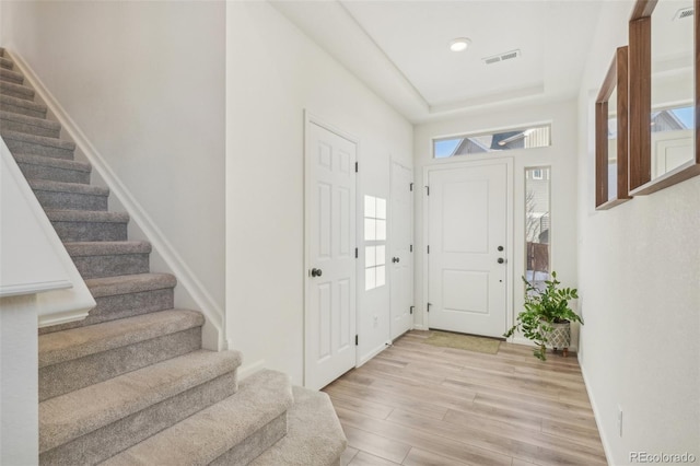 entrance foyer with a tray ceiling and light hardwood / wood-style flooring