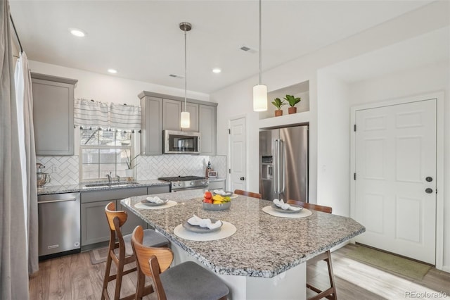 kitchen featuring hanging light fixtures, high end appliances, a kitchen island, and a breakfast bar