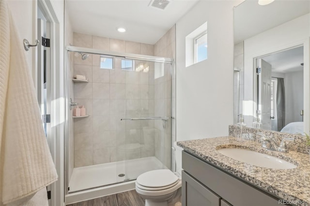 bathroom with a healthy amount of sunlight, a shower with door, and vanity