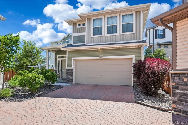 18372 E 100th Pl, Commerce City, CO 80022 - view of front facade featuring board and batten siding, an attached garage, decorative driveway, and stone siding