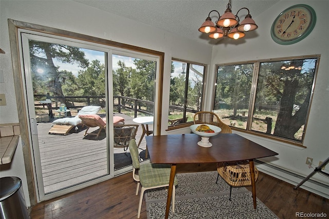 dining area featuring dark wood-type flooring, a textured ceiling, a baseboard heating unit, and a notable chandelier