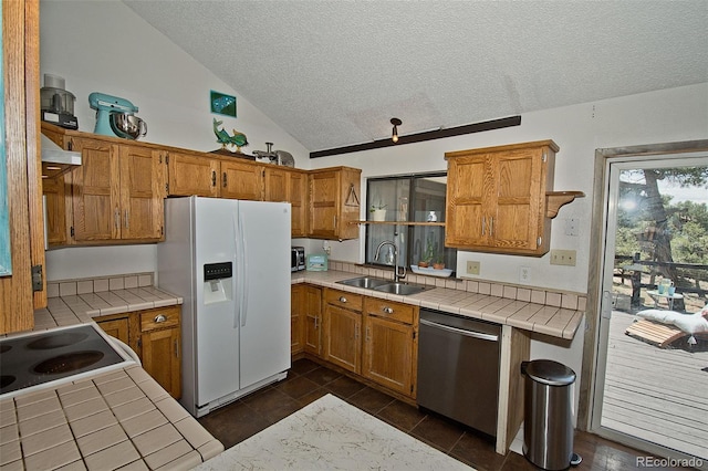 kitchen featuring sink, white fridge with ice dispenser, stainless steel dishwasher, and tile countertops