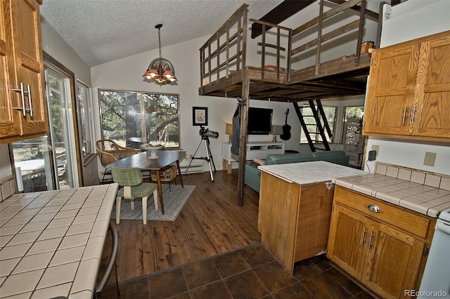 kitchen with decorative light fixtures, vaulted ceiling, a wealth of natural light, and tile counters