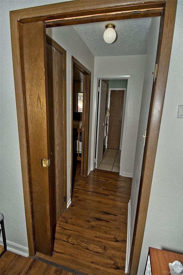 hall with dark wood-type flooring and a textured ceiling