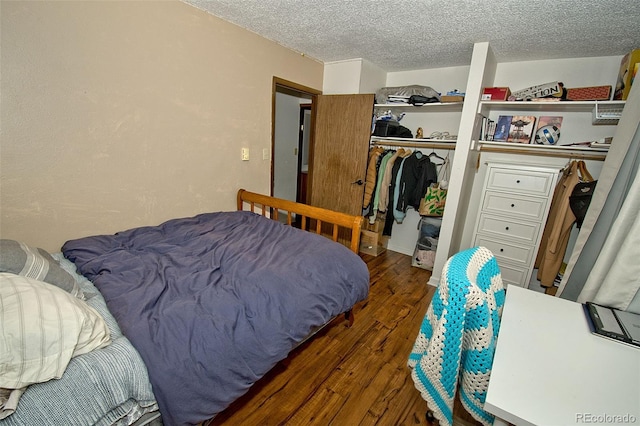 bedroom with dark wood-type flooring, a textured ceiling, and a closet