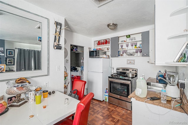 kitchen with visible vents, freestanding refrigerator, open shelves, and stainless steel range with electric stovetop