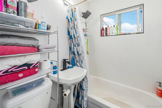 full bath featuring toilet, shower / tub combo, a sink, and a textured wall