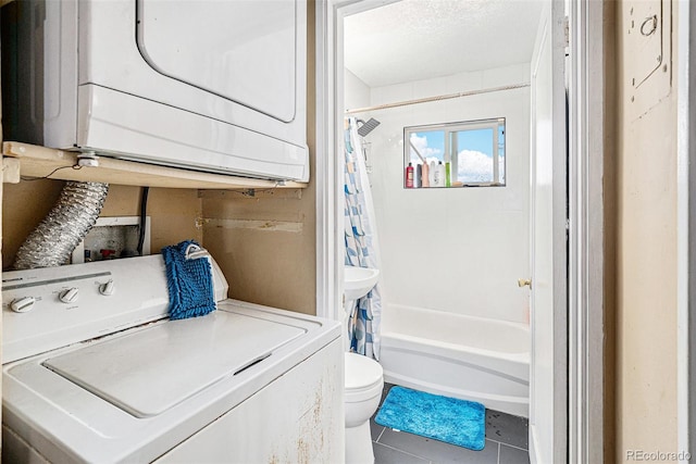 washroom featuring a textured ceiling, laundry area, tile patterned floors, and stacked washer / drying machine