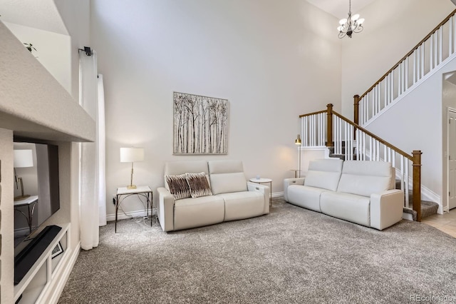 carpeted living room with baseboards, a high ceiling, stairs, and a notable chandelier