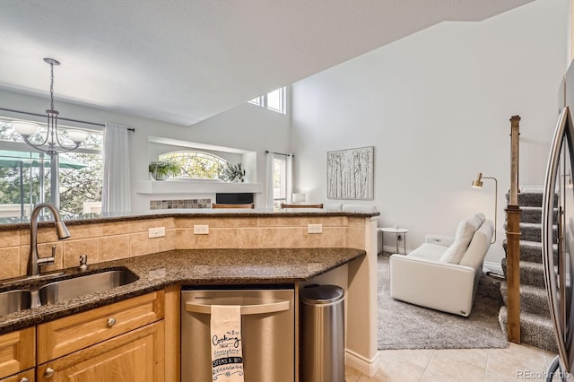 kitchen featuring stainless steel appliances, dark stone countertops, a sink, light tile patterned flooring, and open floor plan