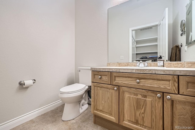 half bath featuring baseboards, vanity, tile patterned flooring, and toilet