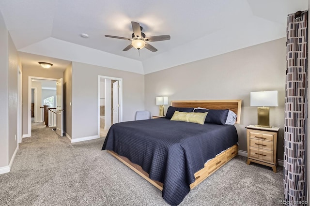 carpeted bedroom featuring baseboards, a tray ceiling, connected bathroom, and ceiling fan