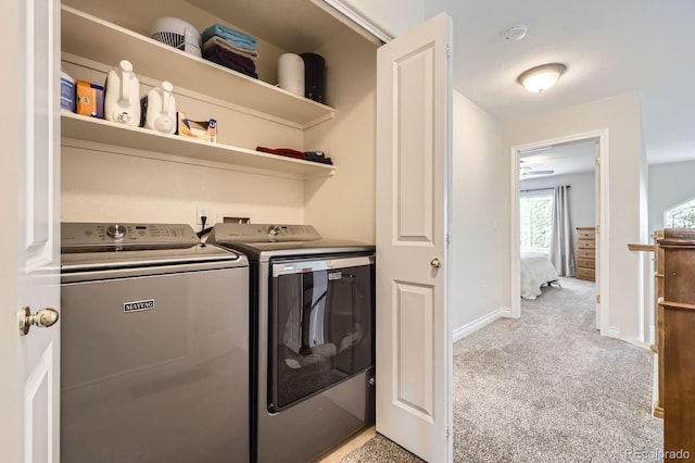 laundry room featuring washing machine and clothes dryer, light carpet, baseboards, and laundry area
