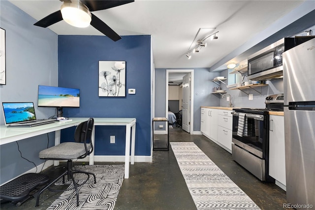 kitchen featuring ceiling fan, built in desk, white cabinetry, and stainless steel appliances