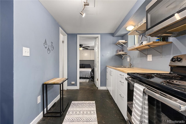 kitchen with butcher block counters, white cabinetry, sink, ceiling fan, and stainless steel appliances