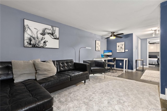 living area featuring ceiling fan, baseboards, and wood finished floors