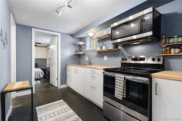 kitchen with stainless steel appliances, butcher block countertops, a sink, and open shelves