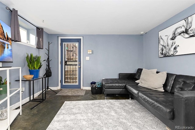 living area featuring concrete flooring and baseboards
