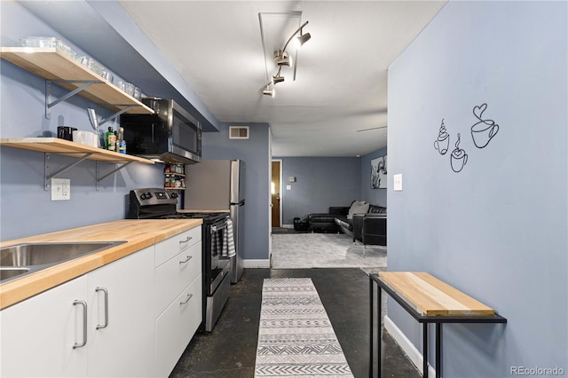 kitchen featuring visible vents, white cabinetry, finished concrete flooring, wooden counters, and appliances with stainless steel finishes