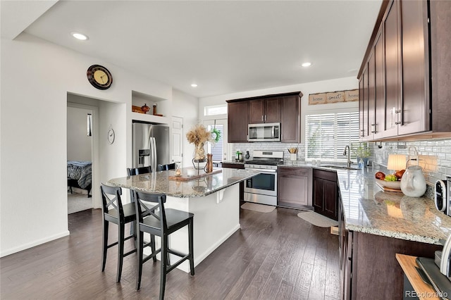 240 S Oak Hill St, Aurora, CO 80018 - kitchen featuring stainless steel appliances, healthy amount of natural light, dark brown cabinets, a breakfast bar, and recessed lighting