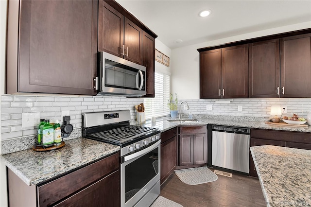 240 S Oak Hill St, Aurora, CO 80018 - kitchen with appliances with stainless steel finishes, a sink, dark wood-style floors, dark brown cabinetry, and light stone countertops