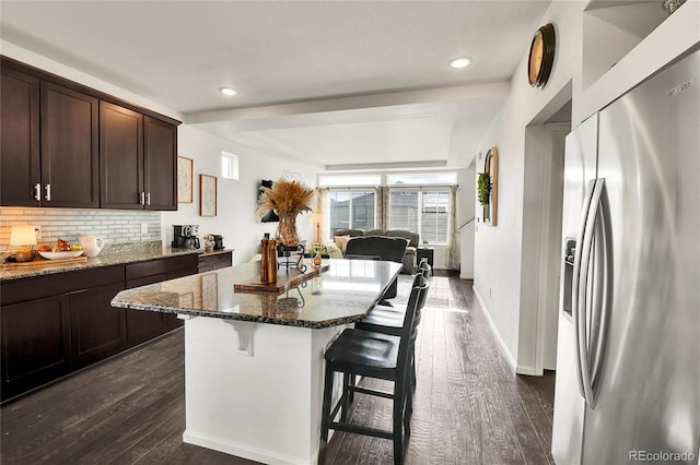240 S Oak Hill St, Aurora, CO 80018 - kitchen with stainless steel refrigerator with ice dispenser, a kitchen bar, dark stone counters, dark brown cabinetry, and backsplash