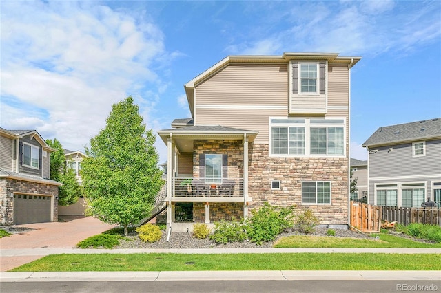 240 S Oak Hill St, Aurora, CO 80018 - view of front facade featuring stone siding, driveway, a garage, and a balcony