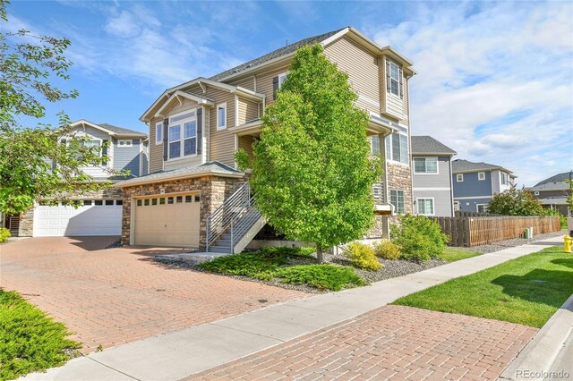 240 S Oak Hill St, Aurora, CO 80018 - view of front of home with stone siding, an attached garage, decorative driveway, and a residential view