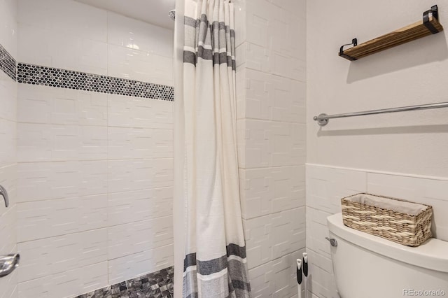 7640 S Monaco Cir W, Centennial, CO 80112 - bathroom featuring tile walls, a tile shower, and wainscoting