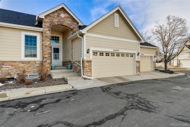 view of front of property featuring a garage, stone siding, and driveway