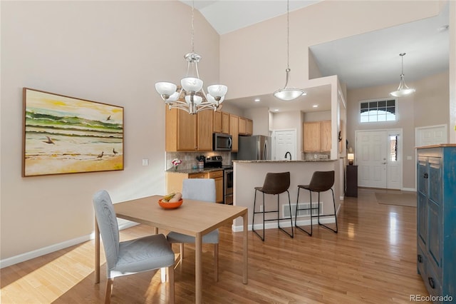 interior space featuring high vaulted ceiling, light wood-type flooring, and baseboards