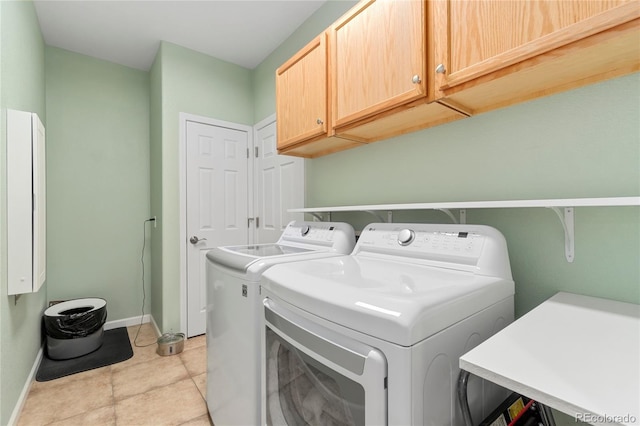 washroom featuring cabinet space, baseboards, and washer and clothes dryer